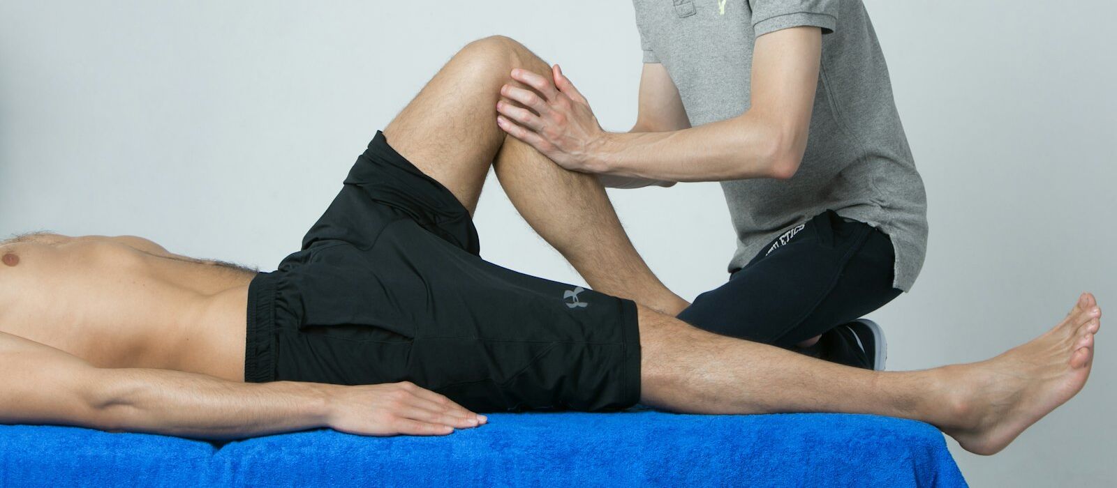 Hände untersuchen das angewinkelte Knie eines liegenden Patienten